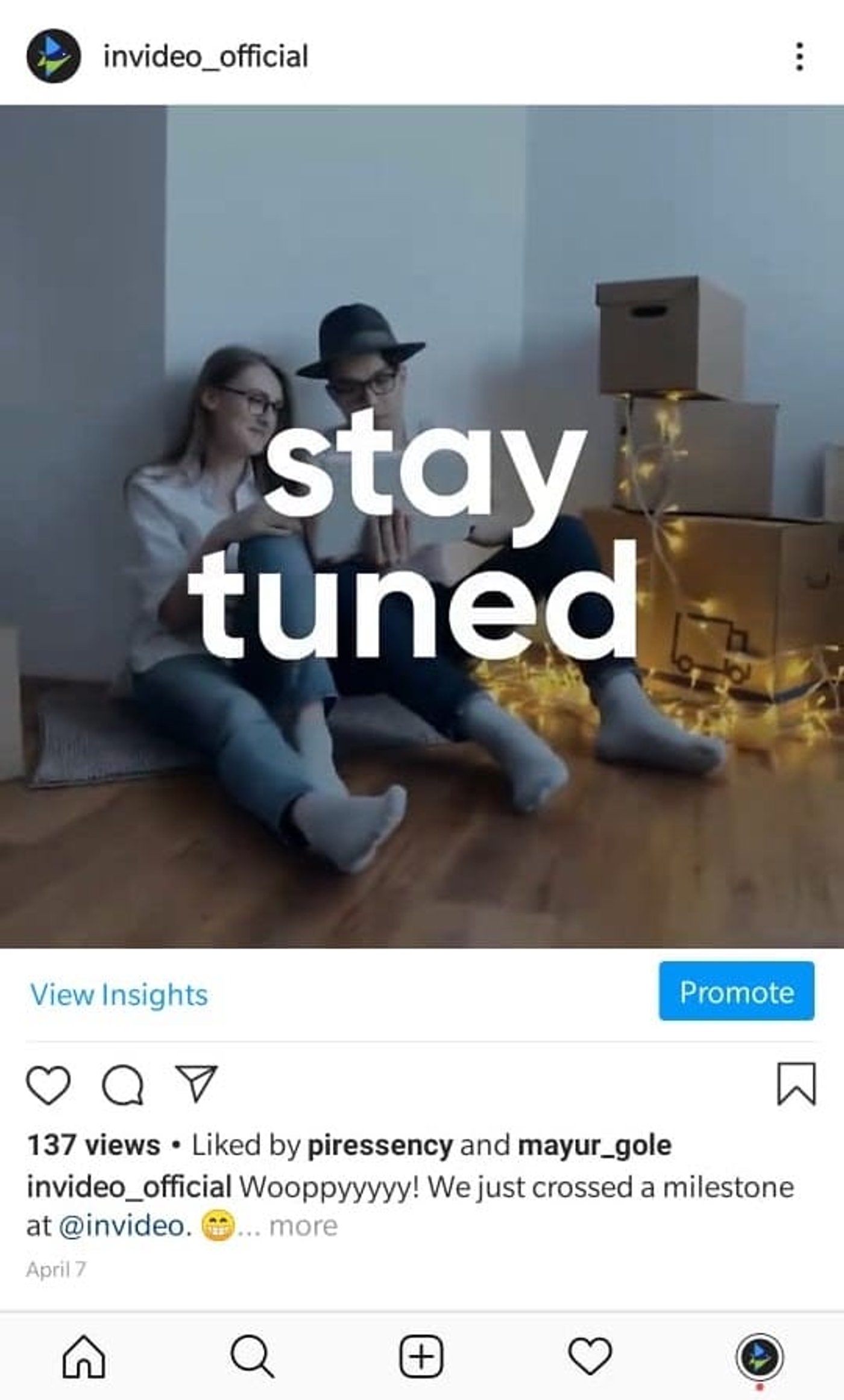 Post de feed de instagram de InVideo con una pareja sentada en el piso de la sala, mirando su notebook junto a unas cajas de mudanza con luces