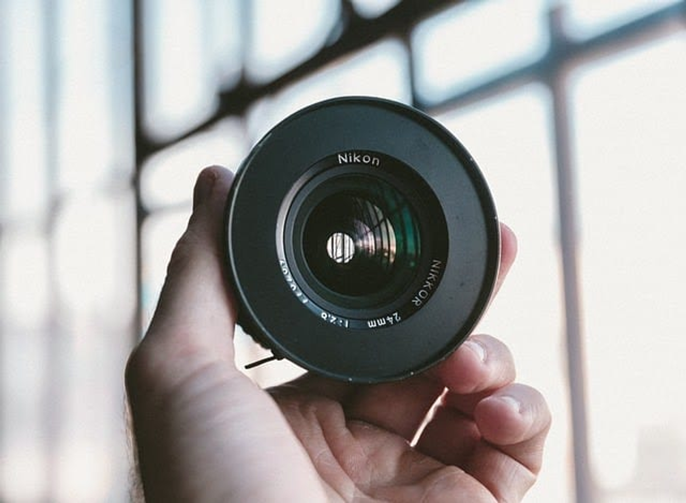Mano sujetando los lentes Nikon de una cámara profesional