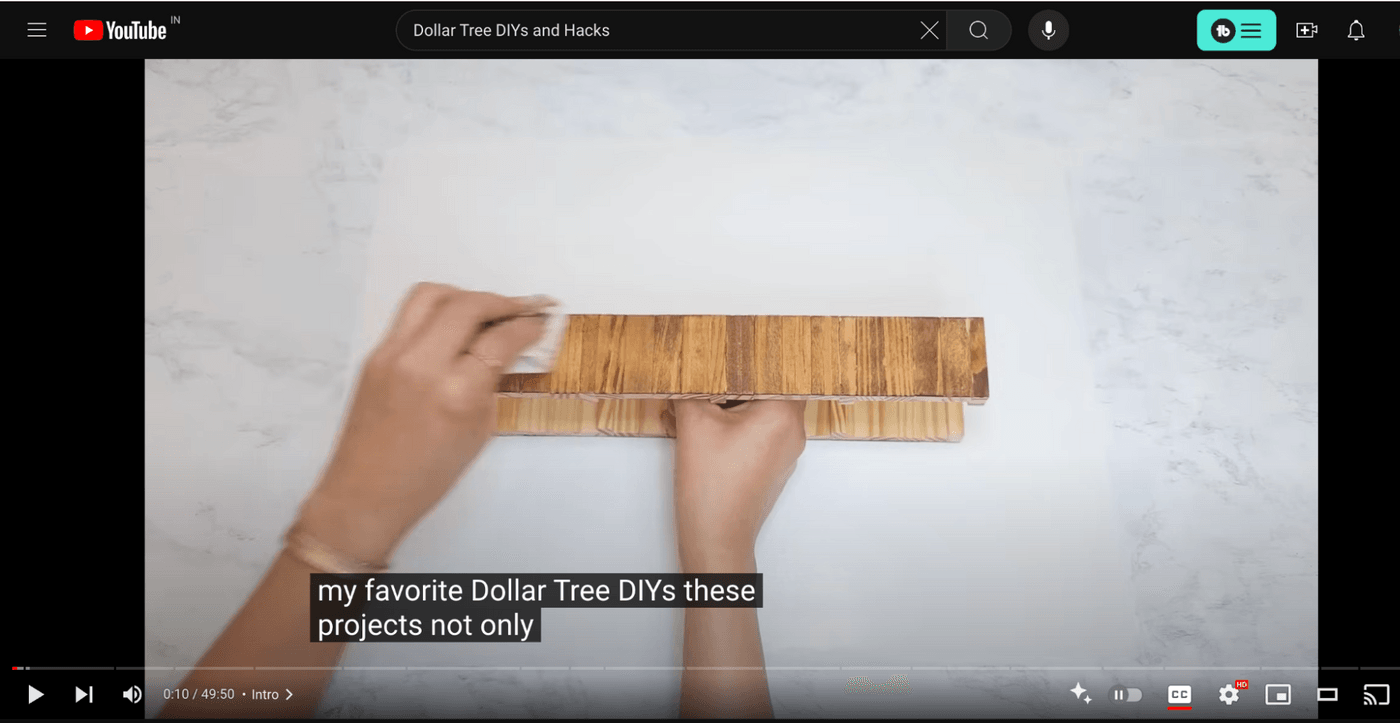 Hands crafting Dollar Tree DIY project with subtitles on YouTube video.