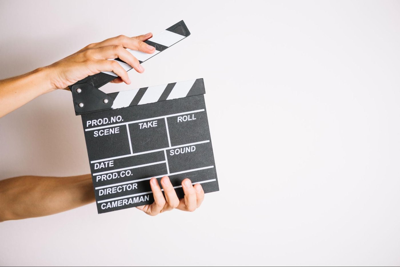 Hands holding a classic black and white film clapperboard against plain white background