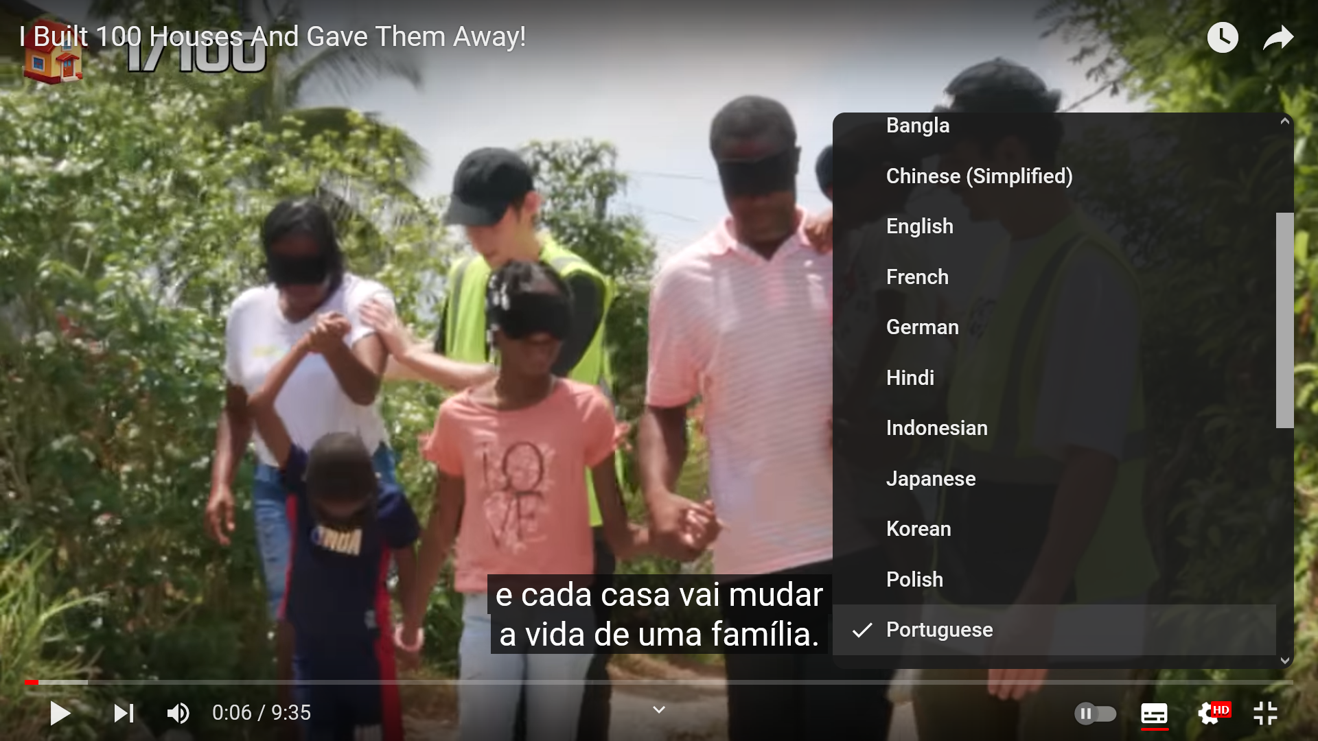 People holding hands blindfolded with subtitles in Portuguese saying every house changes lives.